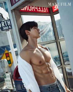 a shirtless young man standing in front of a store with his hands on his hips