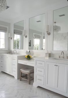 a white bathroom with two sinks and large mirrors on the wall, along with stools