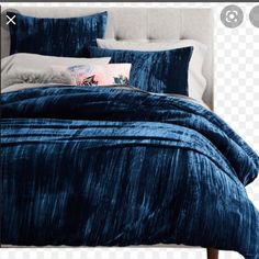 an image of a bed with blue comforter and pillows on the headboard png