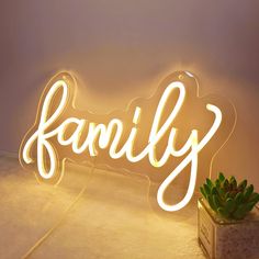 a neon sign that says family with a succulent plant in front of it