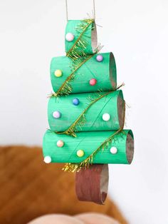 a christmas tree made out of toilet paper rolls is hanging from a string with colored candies on it