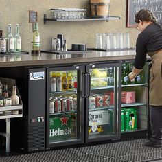 a woman standing in front of a refrigeration unit filled with drinks and beverages