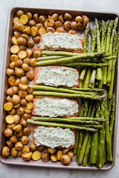 asparagus, potatoes and salmon on a baking sheet with dip in the middle