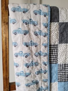 a blue truck quilt hanging on the side of a wall