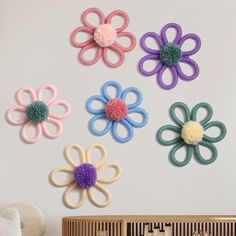 six crocheted flowers are hanging on the wall next to a wooden comb rack