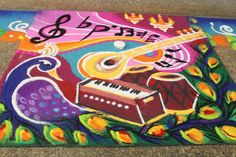 a colorful painting on the ground with an instrument and music notes written in black ink