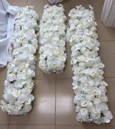 two rows of white flowers sitting on top of a tiled floor