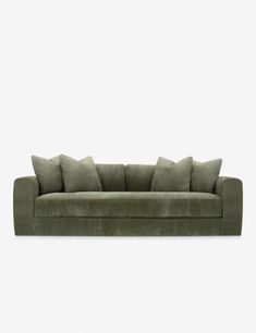 a green velvet couch with four pillows on it's back and one arm facing the camera