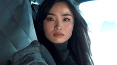 a woman with long black hair sitting in a car