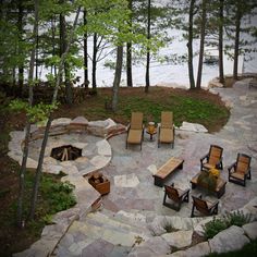 an outdoor fire pit surrounded by chairs and trees