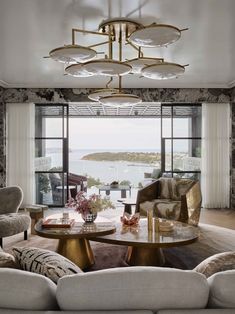 a living room filled with furniture and a large window overlooking the water in front of it