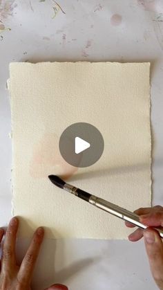 someone is using a brush to paint a piece of paper