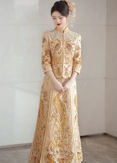 Color: gold Silhouette: A-line Length: long Neckline: mandarin collar Sleeves: three-quarter Fabric: satin Material: polyester Details: sequin embroidery, peacock embellishment A gold Chinese wedding dress for women Captivate everyone by your presence in a gold Chinese wedding dress at the ceremony. Exude elegance and style in this stunning bridal gown made in a luxurious golden shade and decorated with exquisite embroidery. Timeless and chic, this Chinese wedding dress has a charming style and graceful details. Celebrate your culture in this refined wedding ensemble that is inspired by traditional Qun Kwa. It includes a tailored two-piece set that combines a fitted jacket and a feminine A-line skirt. This gold wedding gown is a fantastic option to wear for a tea ceremony as it embodies th Peacock Embellishment, Gold Qipao, Gold Cheongsam, Qipao Wedding Dress, Golden Wedding Dress, Modern Chinese Wedding Dress, Cheongsam Wedding Dress, Embroidery Peacock, Chinese Wedding Dress Traditional