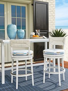 two white stools sitting on top of a rug next to a table and chairs