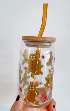 a hand holding a glass with a straw in it and some decorations on the lid