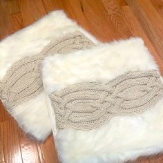 two pieces of white fur sitting on top of a wooden floor next to each other