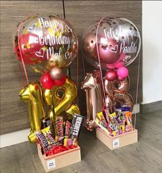 two balloons and some candy in boxes on the floor next to each other with happy birthday messages written on them