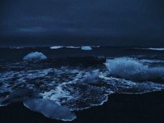 an ocean with icebergs floating in the water and dark clouds above it at night