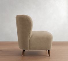 a beige chair sitting on top of a wooden floor next to a white wall in an empty room