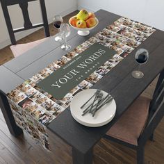 the table is set with two plates and wine glasses on it, next to a bowl of fruit