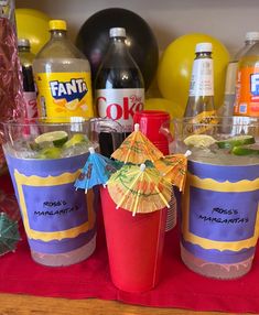 there are two cups with drinks in them on the table next to soda bottles and balloons