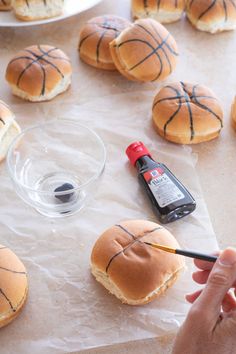 someone is painting the buns with black paint on them and then they are covered in basketball - themed icing