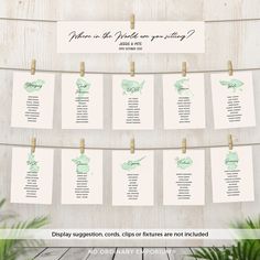 the seating chart for an outdoor wedding is hanging on a wooden wall with clothes pins