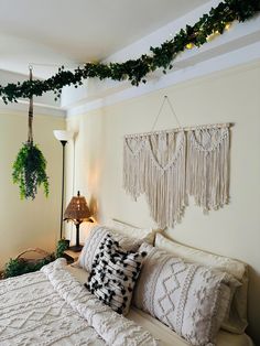 a white bed topped with lots of pillows next to a wall mounted plant and lamp