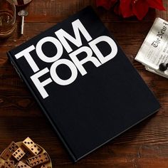 the tom ford book sits on a table next to some wine glasses and other items