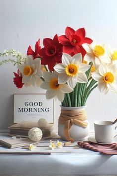 a vase filled with white and red flowers on top of a table next to a cup