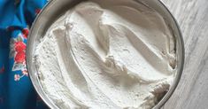 a bowl filled with whipped cream sitting on top of a wooden table next to a blue towel