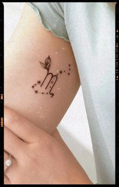 a woman's arm with a flower and zodiac sign tattoo on her left side