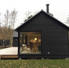 a small black house sitting on top of a lush green field