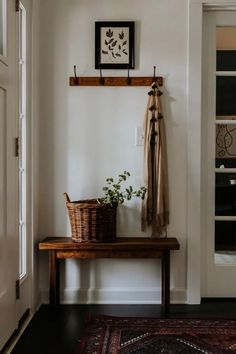 a wooden bench sitting next to a white wall with a potted plant on it