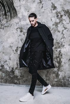 a man in black coat and sneakers walking