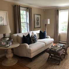 a living room filled with furniture and windows covered in shades of brown, blue and white