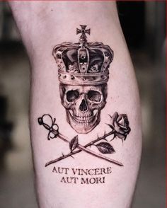 a skull with a crown and two crossed swords on it's leg, which reads aut vincere aut mori