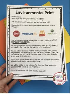 a hand holding up a paper with the words environmental print on it and four different colored papers