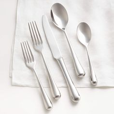 three forks, two spoons and one knife on a white tablecloth with a napkin