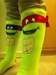 the legs of a person wearing green socks with cartoon faces on them and red ribbon around their ankles