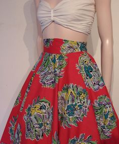 a woman's red skirt with colorful flowers on it and a white top that is attached to a mannequin