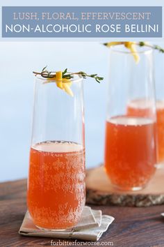 two glasses filled with rose wine sitting on top of a wooden table next to each other