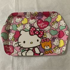 a hello kitty tray with hearts and teddy bears on the front, sitting on a white sheet