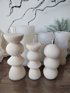 white candles sitting on top of a wooden table next to vases and other items