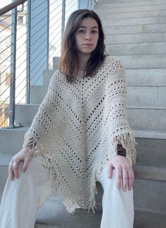 a woman sitting on some stairs wearing a shawl