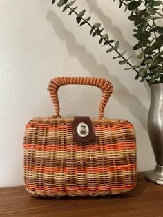 1950s 1960s Multi Colored Coated Wicker Top Handle Handbag, Vintage Purse, Mid Century Accessory  Great warm earthy petite coated wicker top handle handbag made in the 1950s 1960s. It features rigid double handle straps. Metal hardware with a twist closure that works well and closes tightly. Opens to a milk chocolate colored fabric lining.  There is one interior side open pocket. Attached Made In Hong Kong label. There are protective feet on the bottom of the bag. Beautiful vintage condition *the wicker on the exterior has no loose or broken pieces.  The hardware shows normal age related issues.  The lining has a very slight smell (age), there are a few holes also. Measurements: Width x 8" Depth x 3.5" Height w/o handle x 5.5" Handle drop x 5 1/4" Vintage Orange Satchel Bag, Vintage Orange Shopping Bag, Vintage Satchel Bags For Vacation, Vintage Satchel For Vacation, Vintage Brown Bags For Spring, Vintage Bags For Spring Shopping, Vintage Bags For Spring Vacation, Vintage Spring Shopping Bags, Retro Brown Bags For Spring