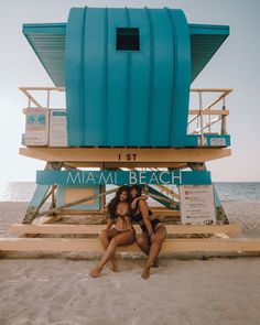 two beautiful women sitting on top of a lifeguard tower