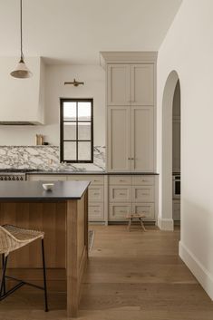 a large kitchen with white cabinets and wood flooring on the counter top, along with a bar stool