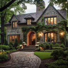 a stone house with lots of windows and plants growing on the front door, along with steps leading up to it