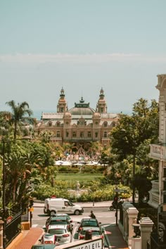 cars parked in front of a large building on the side of a road with palm trees